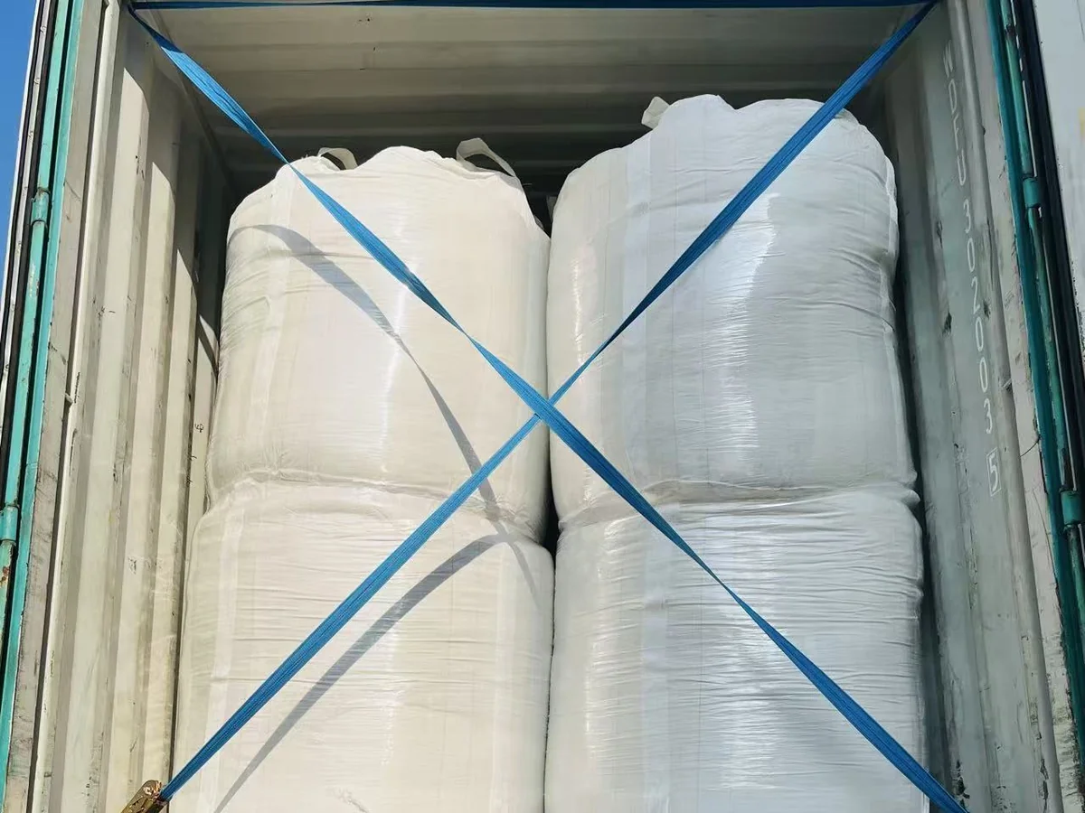 Bulk cat litter bags secured with blue straps inside a shipping container.