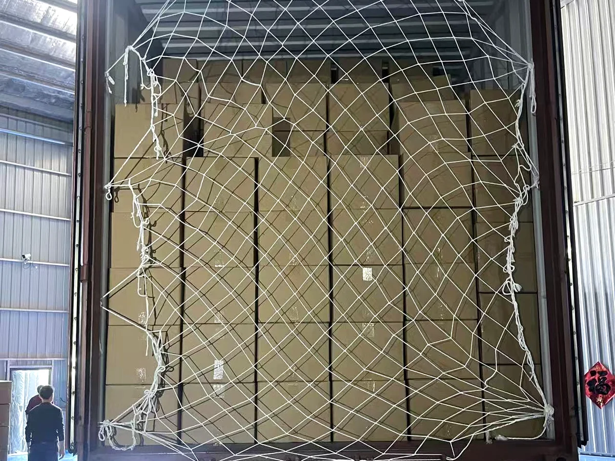 Cardboard cartons secured with a white cargo net inside a warehouse.